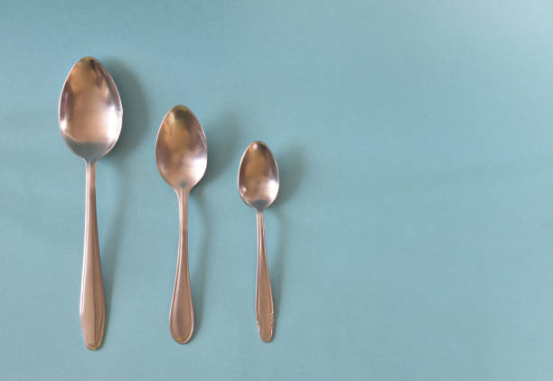 istock Three spoons laid out parallel to the bottom up and isolated on a light blue background. 1318264815