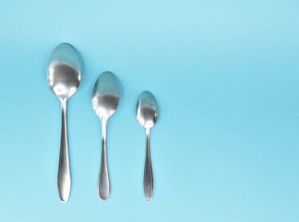istock Three spoons laid out parallel to the bottom up and isolated on a light blue background. 1318264829