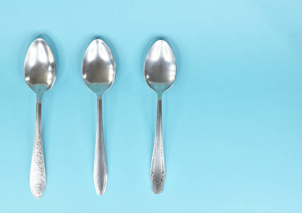 istock Three tablespoons lying parallel to each other and isolated on a light blue background. 1318265465