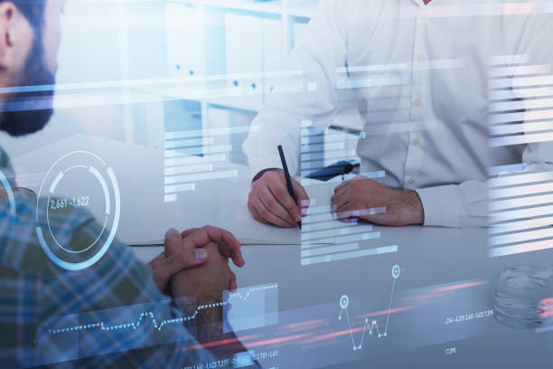 istock Two businessmen sitting at workplace in office and analyzing sto 1318265910