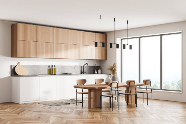 istock Stylish interior of bright and white modern kitchen room with dining table and chairs. Open space zone. big window with view. 1318268067
