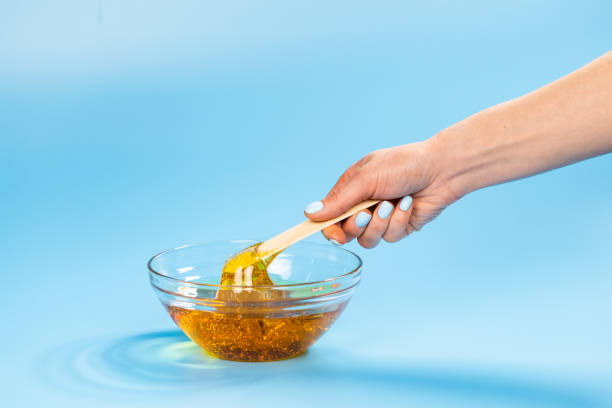 istock Liquid yellow paste for sugaring on blue background. Hair removal and depilation concept. 1318268205