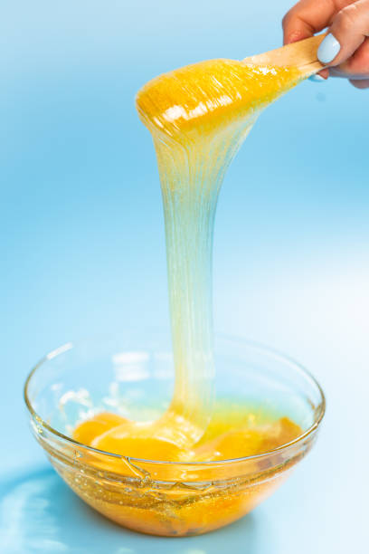 istock Liquid yellow paste for sugaring on blue background. Hair removal and depilation concept. 1318269161