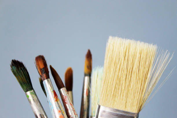 istock Old and new brushes with dried paint on a gray background. Artistic background 1318271236
