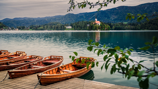 View on pier with boats and church on Bled lake, Slovenia