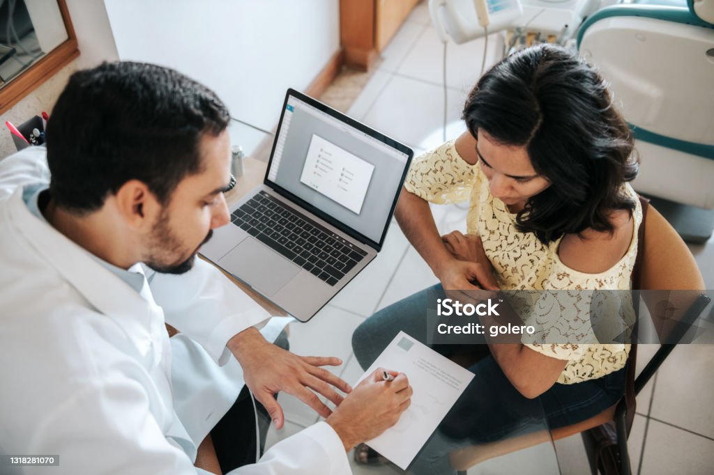 male doctor signing prescription for female patient bearded doctor signing prescription for female patient in in doctors office Medical Referral Stock Photo