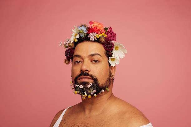 Bearded male with floral makeup Androgynous male having flowers makeup. Bearded male with floral makeup on pink background. gender fluid photos stock pictures, royalty-free photos & images