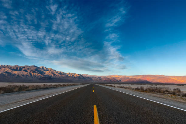 the road passing through the desert against the backdrop of mountains. - asphalt highway desert valley imagens e fotografias de stock