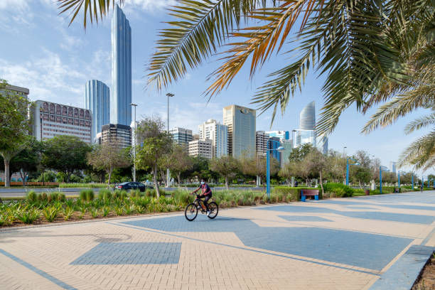 朝、アブダビ・コーニッシュで自転車に乗り、モダンな街並みを背景にした男。 - abu dhabi united arab emirates corniche city ストックフォトと画像