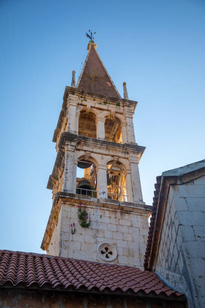 Bell tower of the Church of Our Lady of the Annunciation at the end of a narrow street in the town of Milna on Brac island, Dalmatia, Croatia Milna, Croatia - April 1, 2021: Bell tower of the Church of Our Lady of the Annunciation at the end of a narrow street in the town of Milna on Brac island in Dalmatia, Croatia old catholic church on island brac croatia stock pictures, royalty-free photos & images
