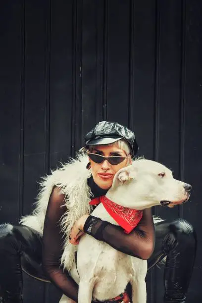 Goth looking fashionable girl model hugging her dogo argentino pet
