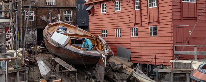 Spakenburg, The Netherlands - February 19, 2021: Man inspecting historic ship at wooden ship wharf in the little pictoresque fishing village Spakenburg Bunschoten in Utrecht in the Netherlands