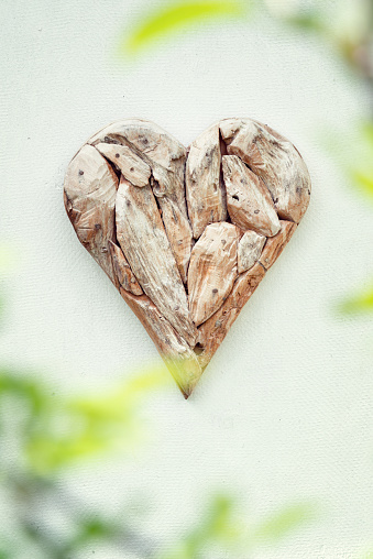 Wooden heart made from driftwood on a white wall.