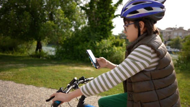 istock Young boy reading bike and using phone in public park 1318318515