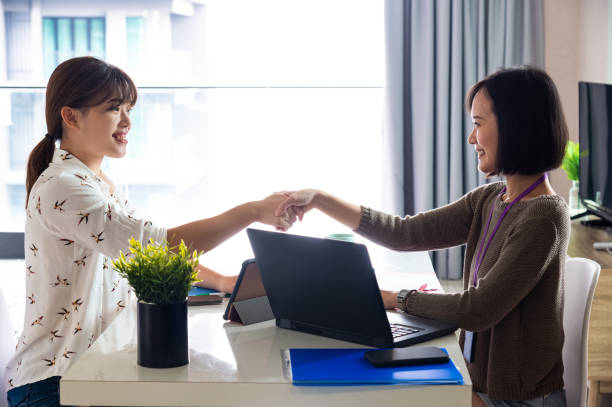 istock Young female entrepreneur shaking hands with business partner after closing a successful project deal during business meeting in modern office. 1318324953