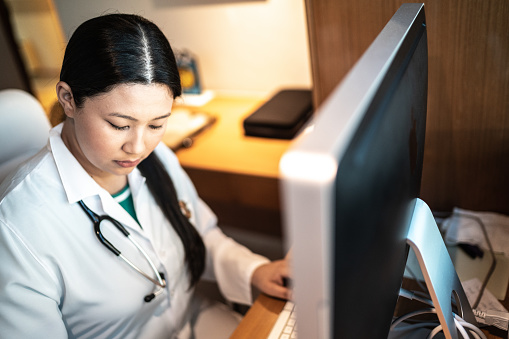 Doctora joven concentrada que trabaja con computadora en el hospital photo