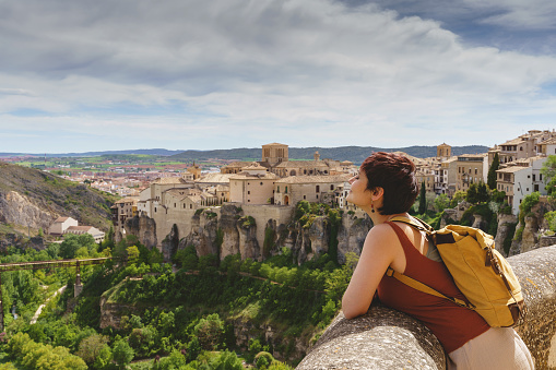 Horizontal view of unrecognizable woman with backpack on holidays looking at the ancient spanish city of Cuenca.