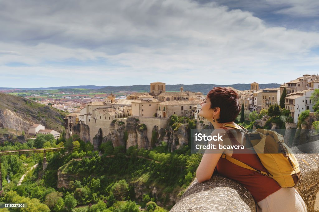 Travel and holidays concept in european cities. Horizontal view of unrecognizable woman with backpack on holidays looking at the ancient spanish city of Cuenca. Travel Stock Photo