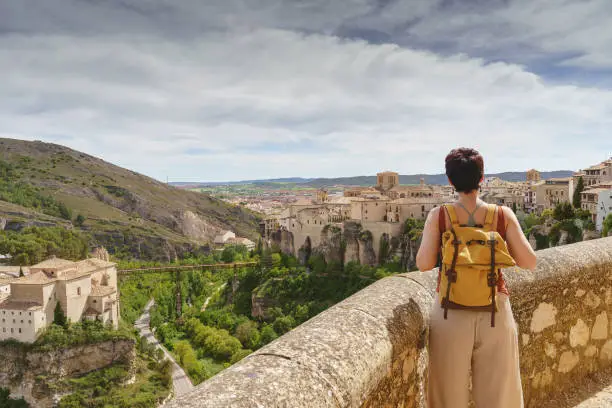 Horizontal view of unrecognizable woman with backpack on holidays looking at the ancient spanish city of Cuenca.