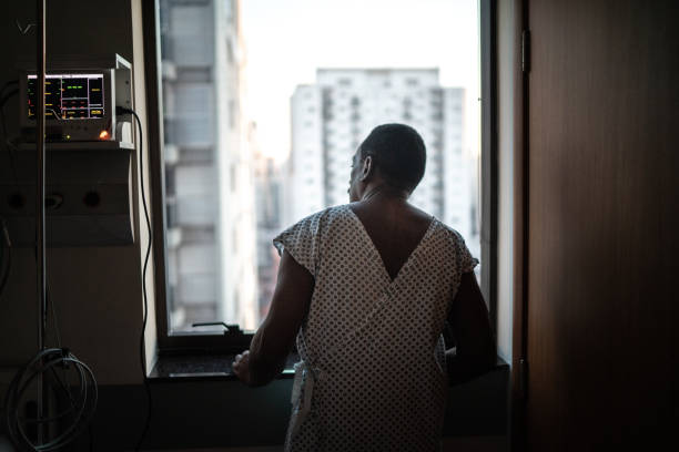 Rear view of a patient at the hospital looking through window Rear view of a patient at the hospital looking through window patience stock pictures, royalty-free photos & images