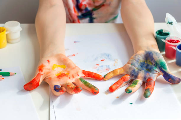 istock Palms painted on childrens hands with multi-colored paints. Childs hobby creativity and art. Children Protection Day. Happy childhood. 1318328779