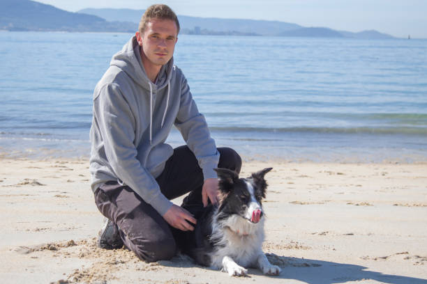istock smiling man sitting on the beach with his dog 1318330754