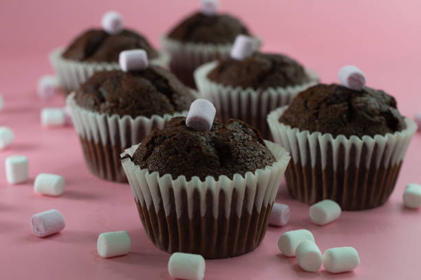 istock Delicious chocolate cupcakes with marshmallows on a pink background. Selective focus 1318330876