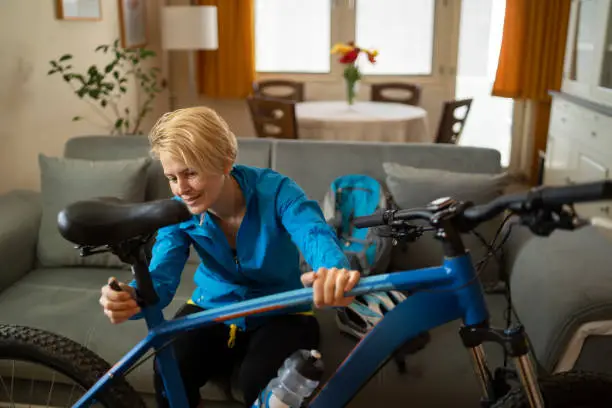 A woman is getting her bicycle ready ensuring everything is prepared for her cycle ride for some low impact daily fitness, she is already wearing her sports clothes