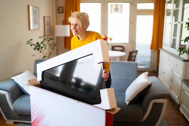 istock A smiling woman unpacks her new television 1318334580
