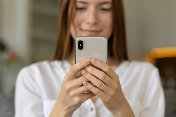 istock Smiling young caucasian millennial woman chatting in social networks using mobile applications sitting on couch at home 1318334847