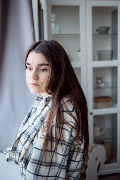 istock Woman looking away while standing near window 1318337018