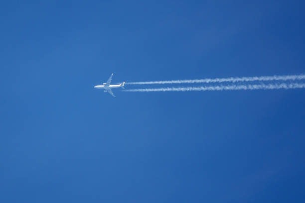istock white airplane flies in the blue cloudless sky, trailing vapor trails behind it 1318341627