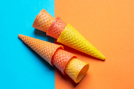 Colorful ice cream cones on orange and blue contrast pastel background top view flat lay