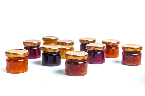 Various fruit jelly marmalade jam spreads in jars on a pile isolated