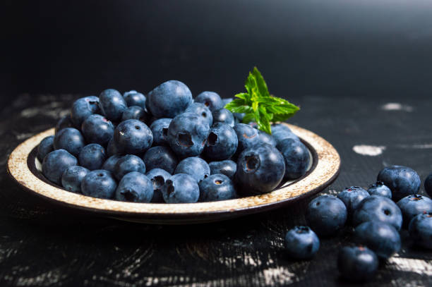 fruta de arándano fresca en un plato - arándano fotografías e imágenes de stock