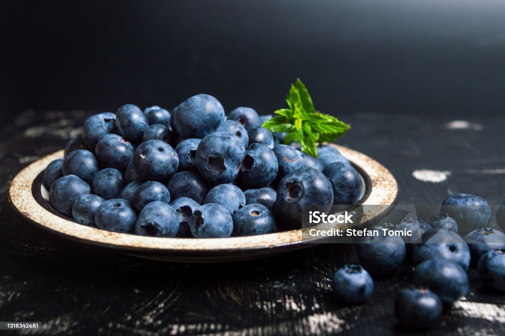 Fresh blueberry fruit on a plate Fresh blueberry fruit on a plate on dark background Blueberry Stock Photo