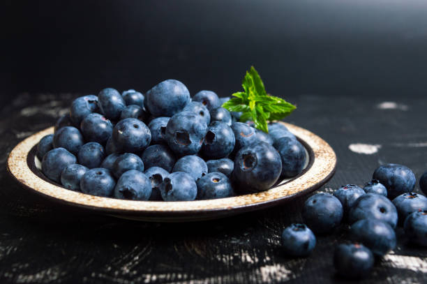 Fresh blueberry fruit on a plate Fresh blueberry fruit on a plate on dark background bilberry fruit stock pictures, royalty-free photos & images