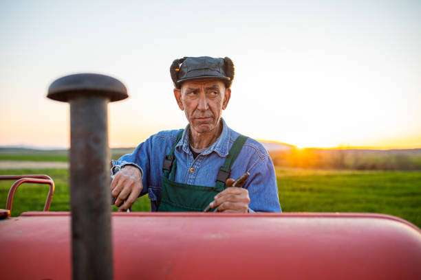 istock Senior farmer fixing his tractor in the field 1318343020
