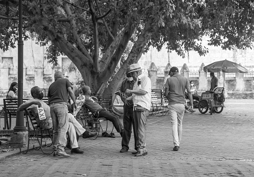 May 10, 2021 Santo Domingo, Dominican Republic. dominican men socialising having conversation with a taxi driver sitting on the bench.