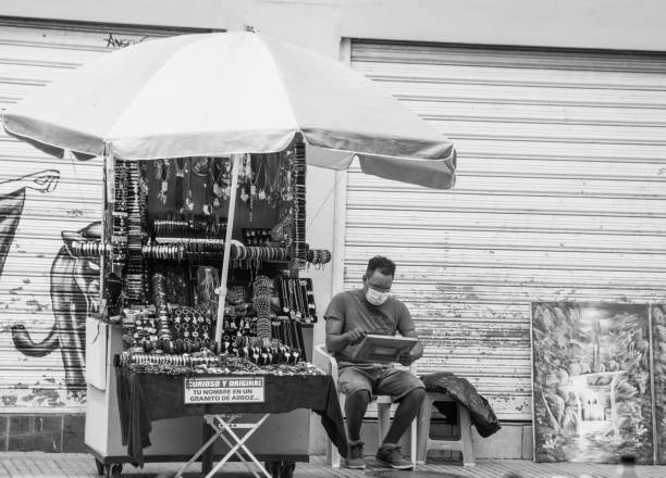 May 10, 2021 Santo Domingo, Dominican Republic high contrast image of a man sitting under umbrella selling souvenirs in the colonial district of the capital city.