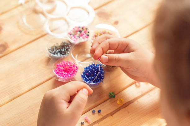 istock The child makes jewelry with his own hands, stringing colorful beads on a thread 1318344943