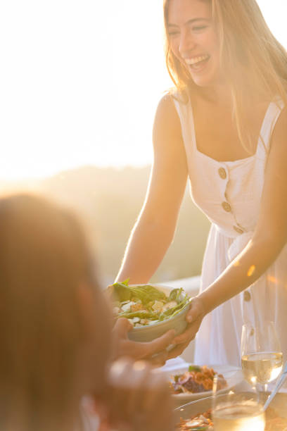 日没時にテーブルの上にサラダを渡す友人や家族。 - vacations restaurant sunlight outdoors ストックフォトと画像