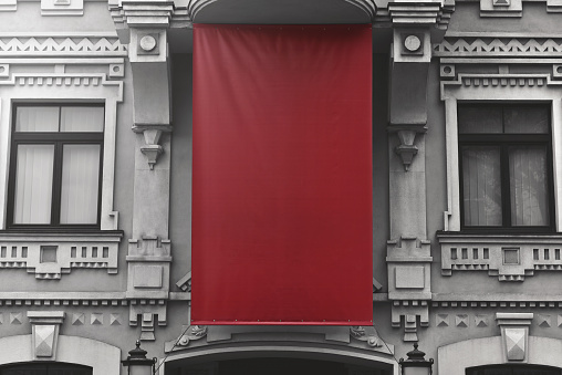 blank red textile banner of outdoors advertising is hang on facade old building