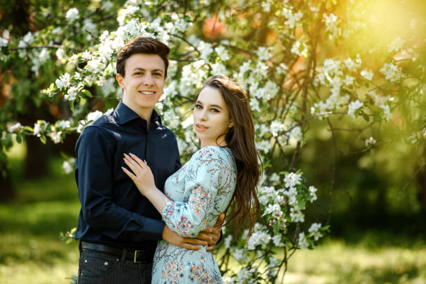 꽃이 만발한 벚꽃 나무에서 포옹하고 미소짓는 젊은 아름다운 부부. - portrait adults apple tree cherry tree 뉴스 사진 이미지