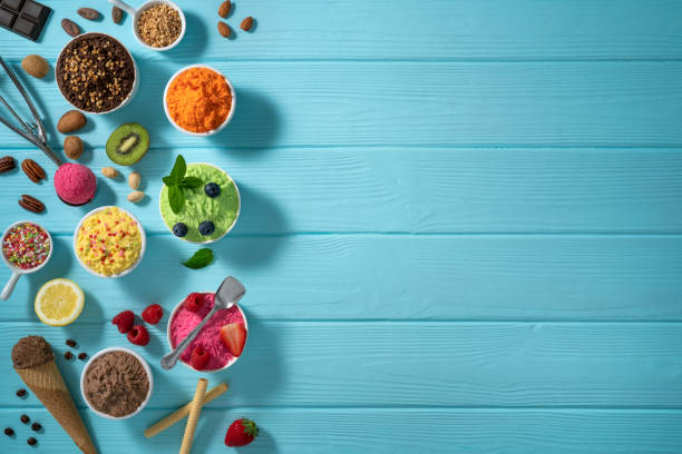Assorted ice cream cups and waffle cones colorful different flavor on blue wood