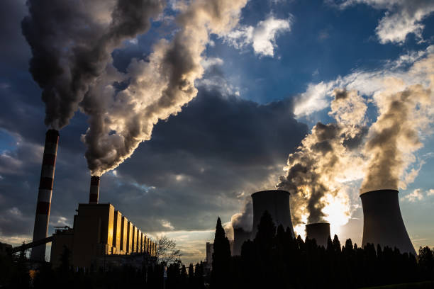 uma vista das chaminés fumantes de uma usina a carvão no pano de fundo de um céu dramático com nuvens. - environmental damage power station factory smoke stack - fotografias e filmes do acervo