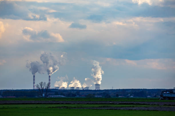 una vista de las chimeneas humeantes de una planta de carbón distante en el horizonte. - global warming power station smoke stack coal fotografías e imágenes de stock