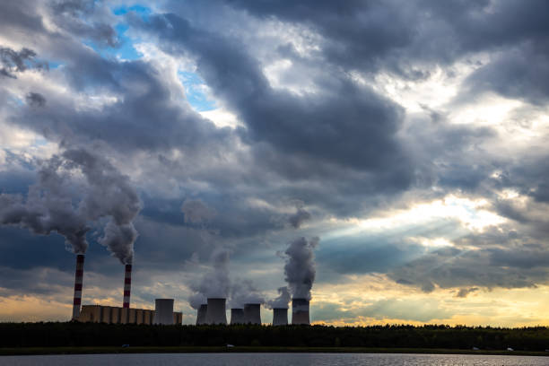 una vista de las chimeneas humeantes de una central eléctrica de carbón en el telón de fondo de un cielo dramático con nubes. - global warming power station smoke stack coal fotografías e imágenes de stock