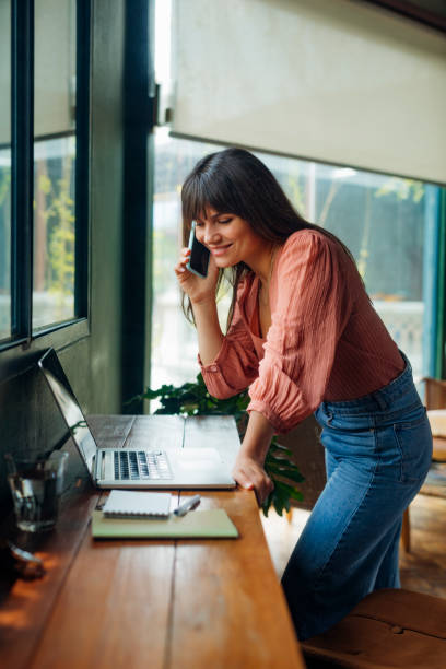 istock Women in Business: Attractive Smiling Businesswoman Talking on the Phone while Working from Home 1318354074