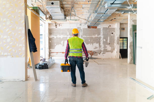 Man standing with drywall and toolbox in his hands in empty house stock photo
